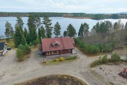Ilmakuva punaisesta vuokramökistä Pielisen rannalla, ympärillä hiekkapolut ja vehreä metsä. Täydellinen majoitus Pohjois-Karjalassa.